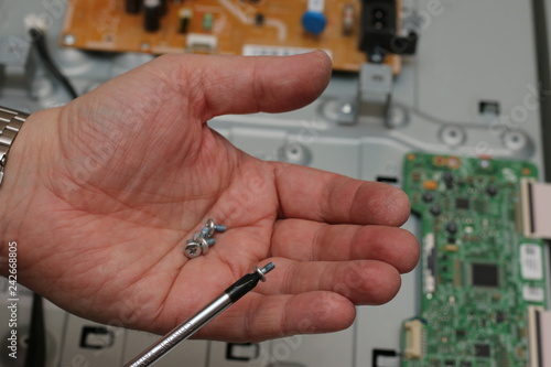 man holding a screwdriver and screws repair tv or pc. fix electrical circuit chip