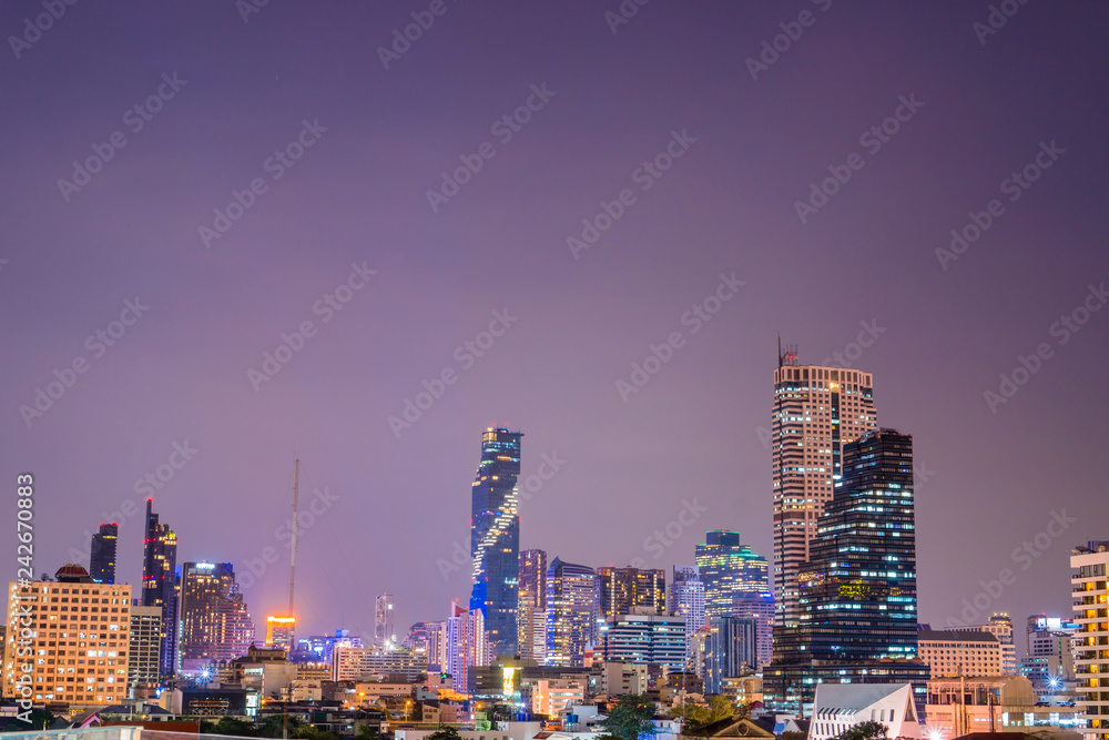 Colorful Abstract Photo blurred of city modern buildings night bangkok cityscape view at twilight time, Decorated with de-focus bokeh cities offices of reflecting building in Bangkok Thailand.