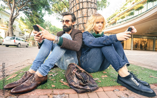 Photos Hipster millennial couple in disinterest moment with smartphone - Apathy concept