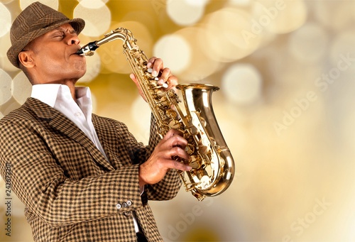 Close-up man playing on saxophone on blurred background