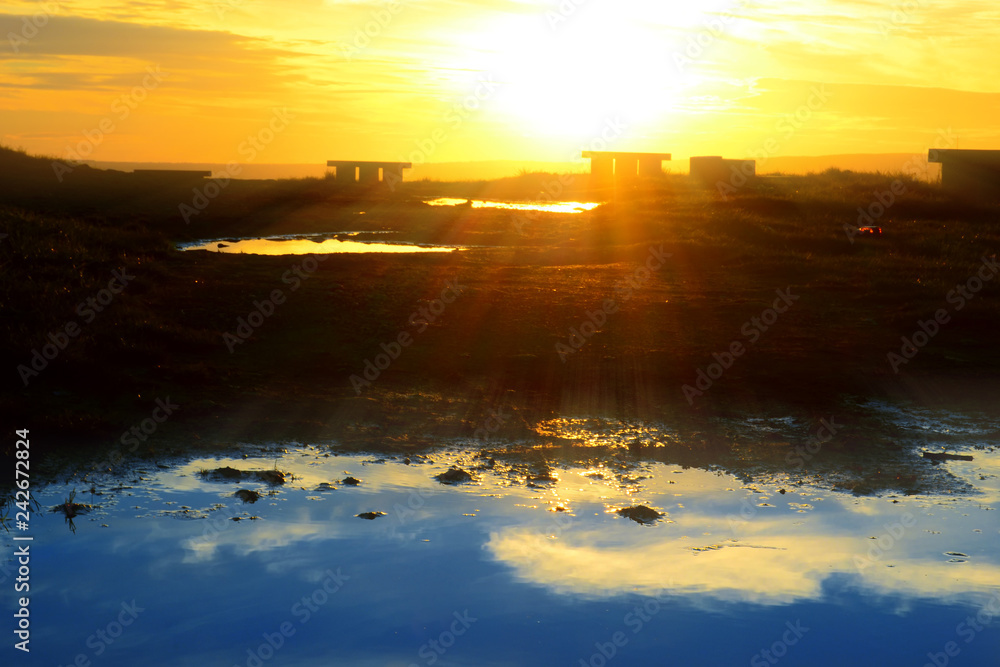  sunlight with a large puddle of water in the foreground 
