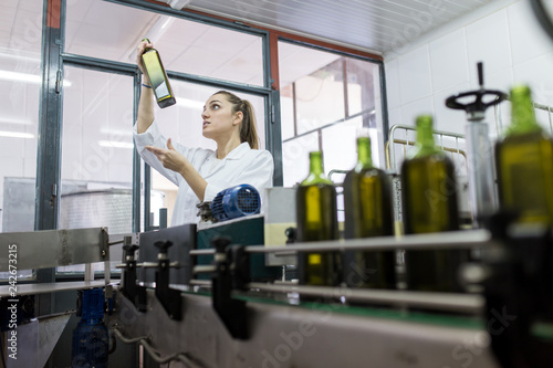 Young woman checking bottles in factory