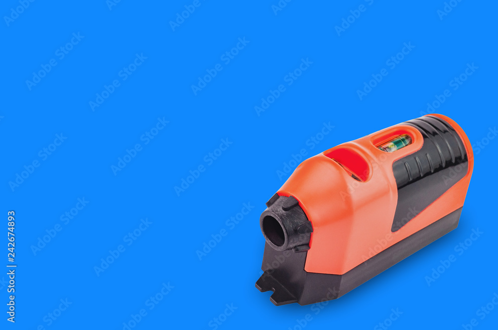 One red and black plastic laser level with water bubble for horizontal or vertical measure on blue background with copy space for your text. Building or repair concept One red and black plastic laser level with water bubble for horizontal or vertical measure on blue background with copy space for your text. Building or repair concept