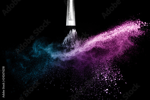 Cosmetic brush with purple and blue ocean cosmetic powder spreading for makeup artist or graphic design in black background, look like a lively and joyful mood.