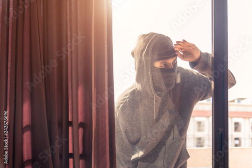 Burglar wearing black clothes and leather coat breaking in a house photo