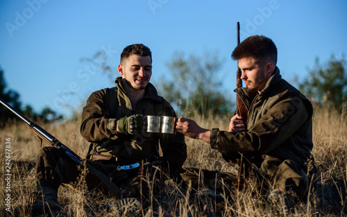 Hunters with rifles relaxing in nature environment. Hunter friend enjoy leisure in field. Hunting with friends hobby leisure. Rest for real men concept. Hunters gamekeepers relaxing. Discussing catch