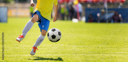 Young Soccer Player Kicking Ball. Horizontal Football Match Image with Blurred Pitch in the Background © matimix