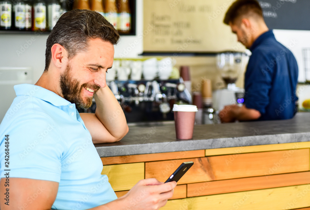 Coffee take away option for busy people. Man mobile reading message cafe barista background. Drink coffee while waiting. Check message. Man smartphone order coffee in cafe. Coffee break concept Coffee take away option for busy people. Man mobile reading message cafe barista background. Drink coffee while waiting. Check message. Man smartphone order coffee in cafe. Coffee break concept