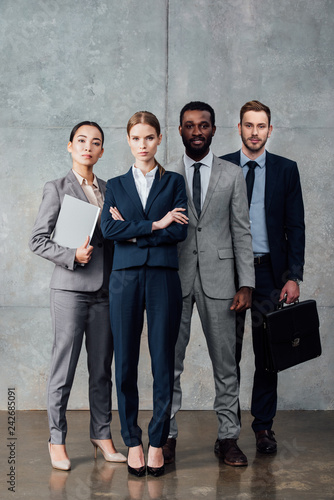 concentrated multiethnic group of businesspeople in formal wear looking at camera and posing