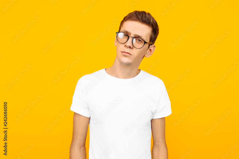 Handsome man in glasses, dressed in a white T-shirt, posing on a yellow background Handsome man in glasses, dressed in a white T-shirt, posing on a yellow background