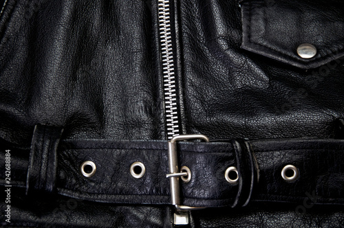 Detail of old black leather police style motorcycle jacket focusing on belt and zipper, showing flap pocket also.