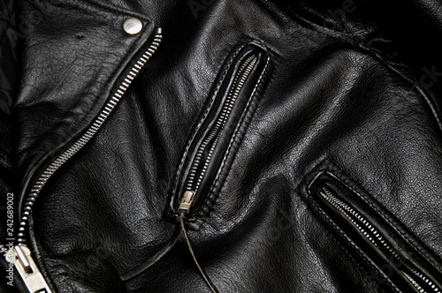 Detail of classic old black leather police style motorcycle jacket focusing on zippers and pockets.