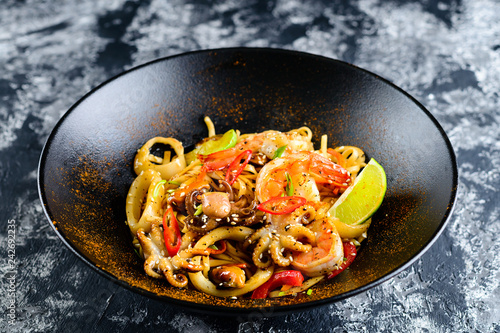 Stir fry noodles with vegetables and seafoods in black bowl