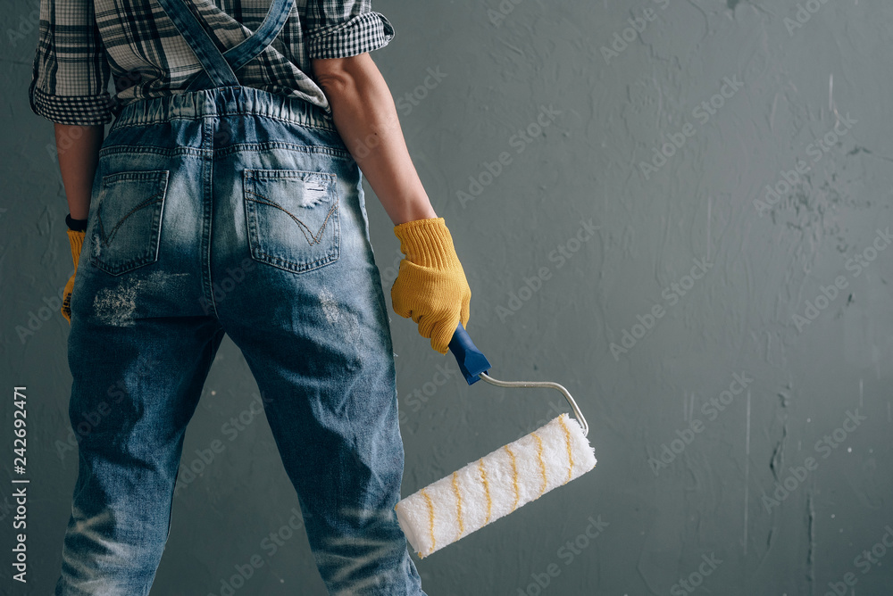 © Mykhailovskyi - a strong-willed woman in a construction helmet, mittens, goggles and overalls is engaged in repair and construction work at home. concept of a strong and independent woman