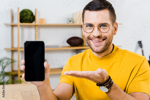 handsome man in glasses showing smartphone with blank screen