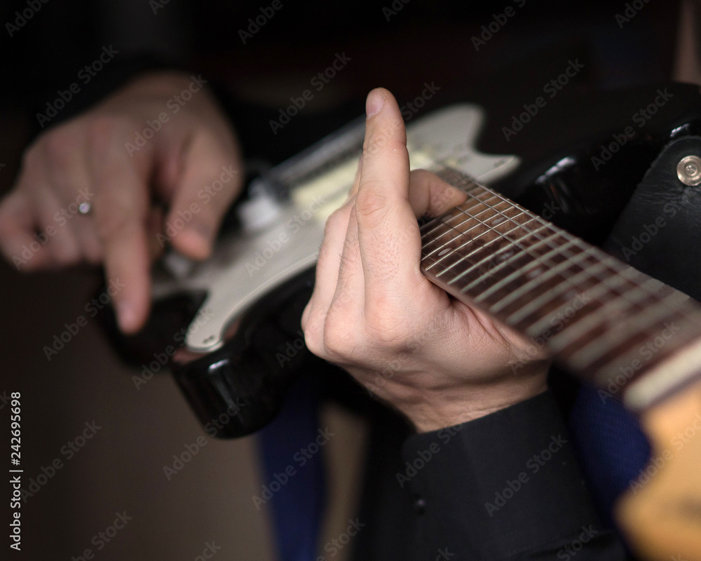 Male hands playing on electric guitar, close up, selected focus