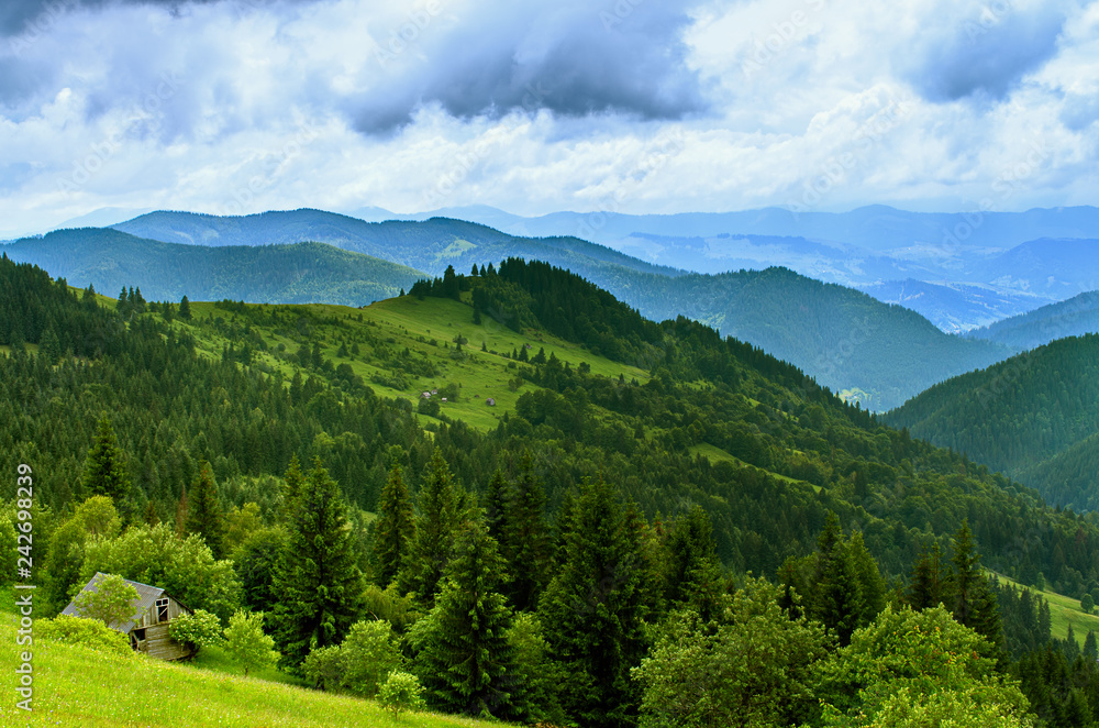 Fototapeta premium Landscape from height to mountain slopes, blue distance, meadow, house. Carpathians Ukraine.