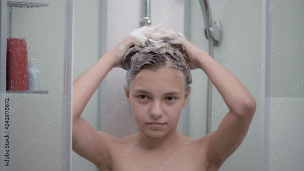 Vidéo Stock Smiling young girl bathing under a shower at home. Beautiful teen girl taking shower and washing in the bathroom. Happy child washing head, face and body with water. | Adobe Stock 