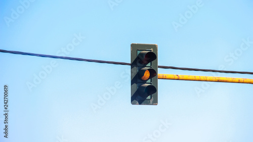 Traffic light with orange light against the sky and wires