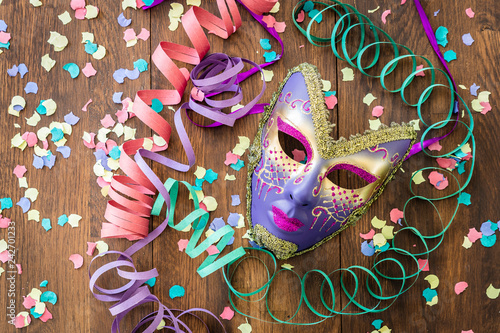 Carnival mask with confetti in a wooden background