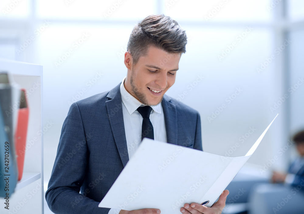 Smiling businessman reading some documents in workplace Smiling businessman reading some documents in workplace