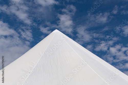 top of white tent against blue cloudy sky