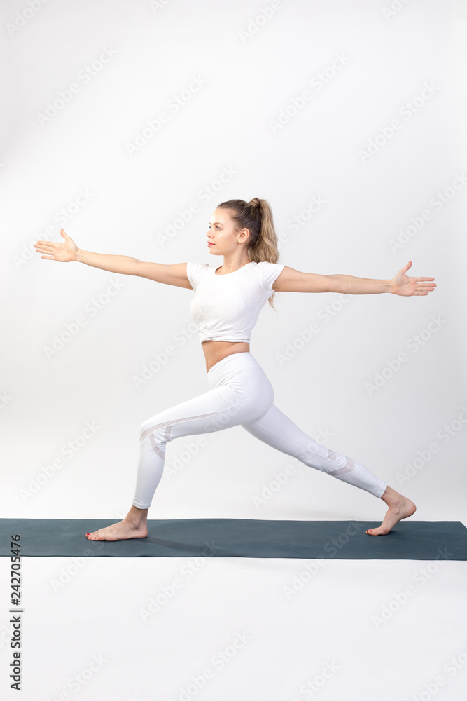 Sporty young woman doing yoga practice on white background.