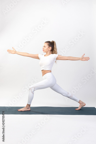 Sporty young woman doing yoga practice on white background.