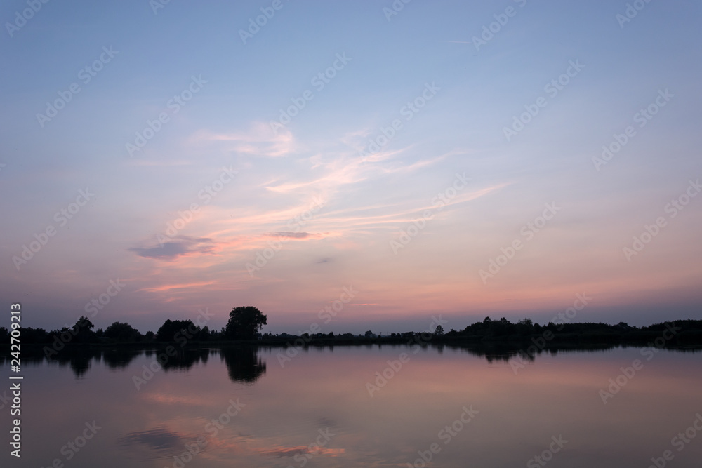 Pink clouds over a calm lake after sunset