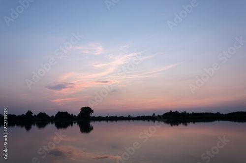 Pink clouds over a calm lake after sunset © darekb22