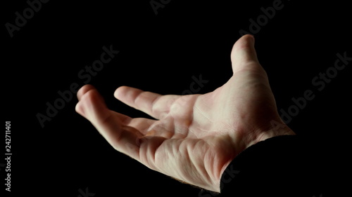 Male hand clenched in fist in rays of light isolated on black background. Fingers slowly open themselves and show empty palm, then clenched back into fist. Presentation concept, slow motion video.