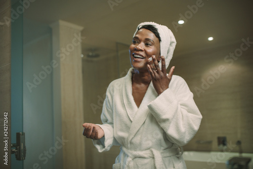 Reflection in mirror of female applying cream on face photo