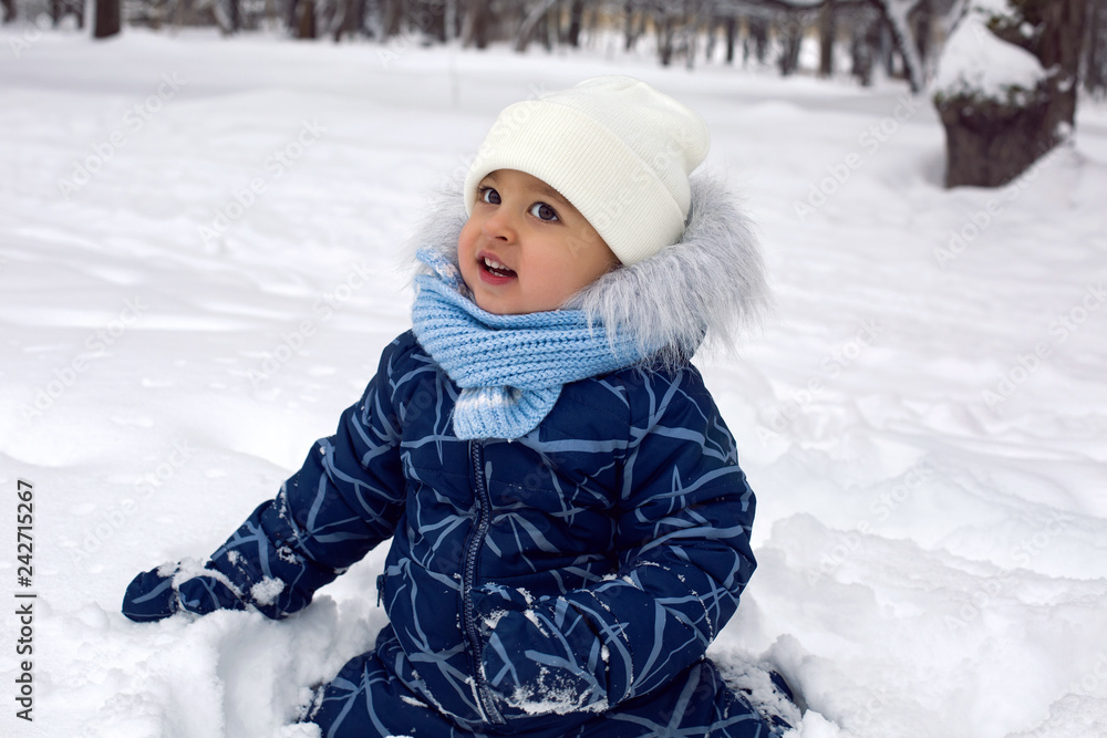 Obraz premium baby boy in the winter in blue overalls on the street