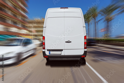 Foto Transporter oder Lieferwagen fährt auf einer Straße bei blauem Himmel und liefert Pakete aus