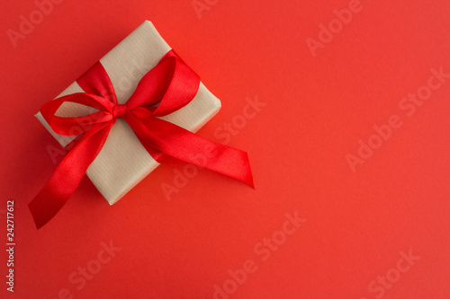Gift with red bow on the red background.Top view.Copy space.