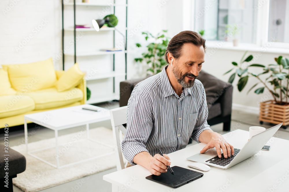 Positive Caucasian man using modern devices and smiling