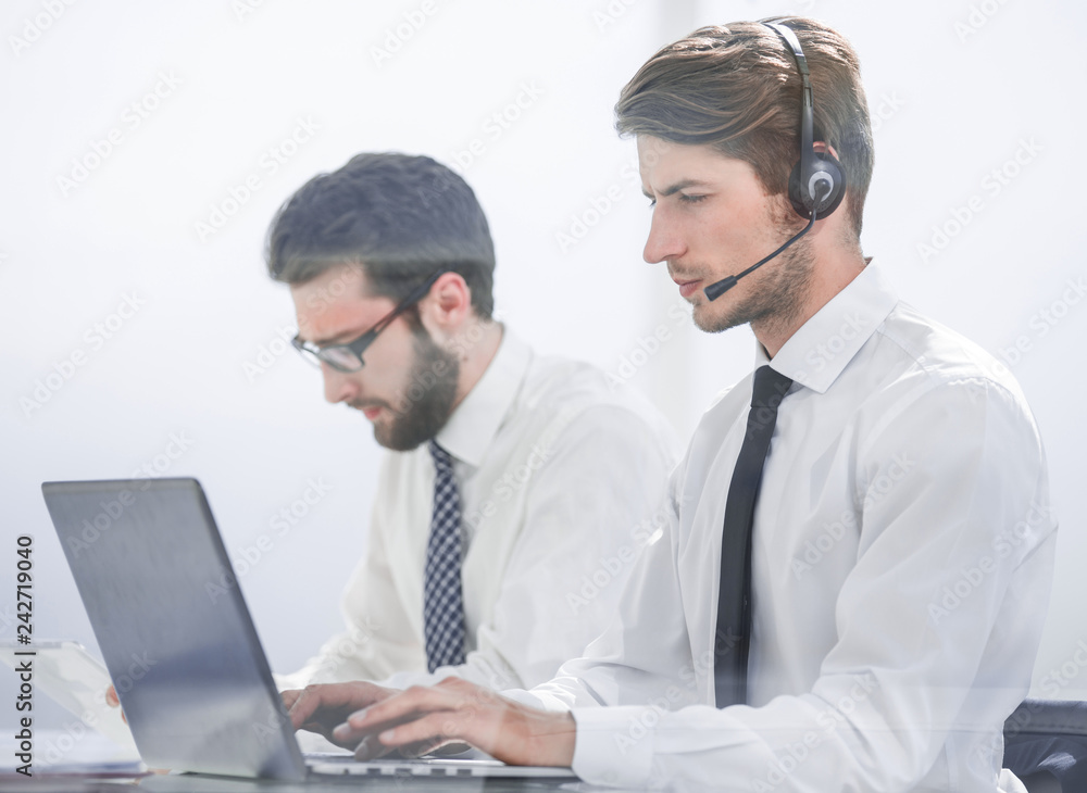 Manager with the headset uses a laptop to work with the client Manager with the headset uses a laptop to work with the client