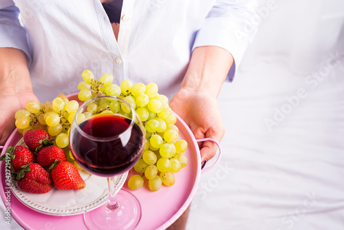 girl in a shirt holds a tray of fruit and wine on white background photo