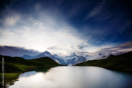 High mountain peaks glowing in the moonlight. Location place Bachalpsee in Swiss alps, Grindelwald valley.