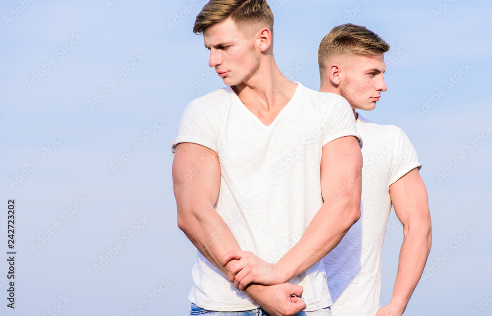 Men twins muscular brothers sky background. Handsome strong twins. Men strong muscular athlete bodybuilder posing confidently in white shirts. Sport lifestyle and healthy body. Attractive twins Men twins muscular brothers sky background. Handsome strong twins. Men strong muscular athlete bodybuilder posing confidently in white shirts. Sport lifestyle and healthy body. Attractive twins