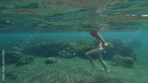 Young woman with snorkeling mask and tube swimming in blue sea waterline view. Woman snorkeling with mask and tube in sea. Underwater view. Coral reef, swimming fish in underwater world. photo