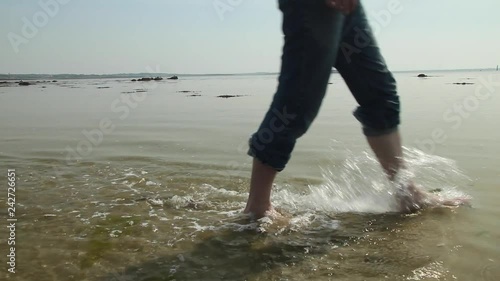 A man walking in shallow water, with only legs in shot. photo