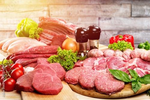 Fresh raw meat background with vegetables on wooden desk