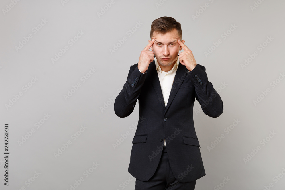 Concerned tired young business man in classic black suit, white shirt stretching eyelids with fingers isolated on grey wall background. Achievement career wealth business concept. Mock up copy space. Concerned tired young business man in classic black suit, white shirt stretching eyelids with fingers isolated on grey wall background. Achievement career wealth business concept. Mock up copy space.
