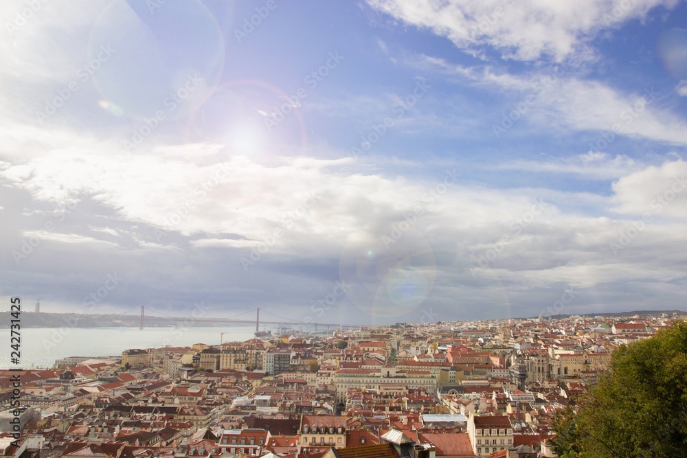 Sunny day in Lisbon. Panoramic view of the red roofs and blue sky with colorful light effects