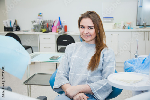 Female patient at dentist cabinet scared of tooth cure. Young woman holding cheek sitting at stomatologist armchair.