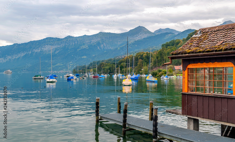 Naklejka premium Lake in Switzerland with boats on a cloudy day with mountains in the background