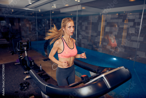 Woman running on treadmill. Gym interior  healthy lifestyle concept.