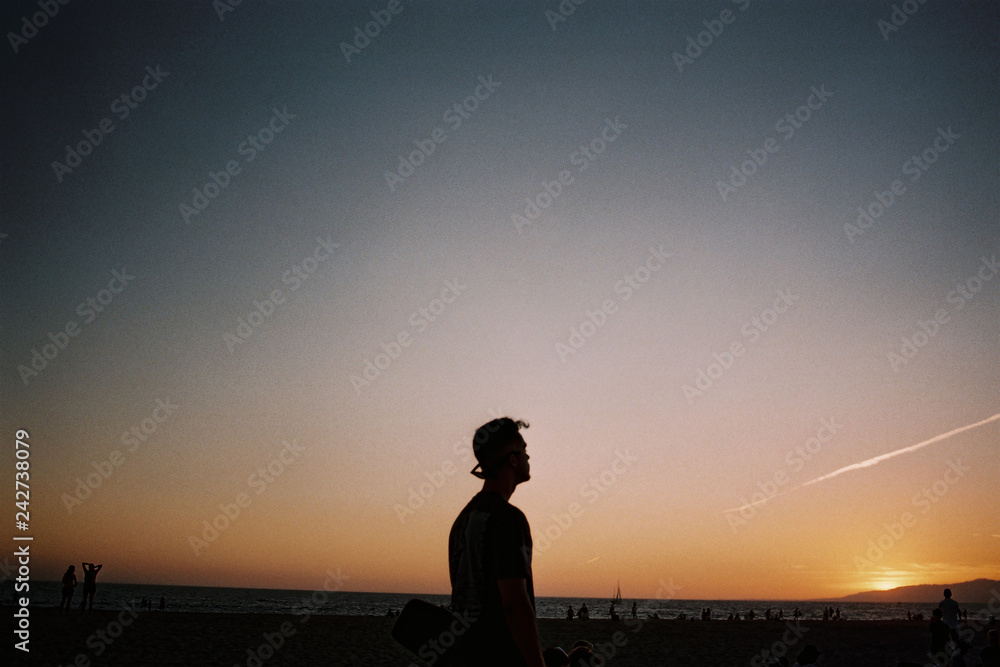 silhouette of man standing on the beach at sunset silhouette of man standing on the beach at sunset