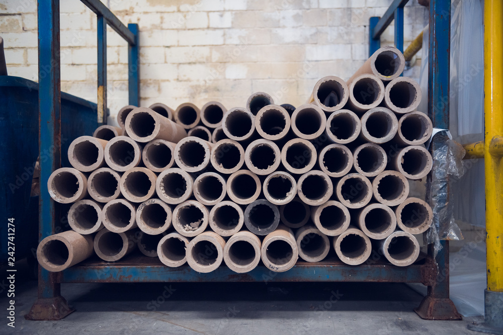 An industrial stack of empty paper cardboard tube rolls waiting to be recycled in a warehouse setting. Industrial waste management. Recycle helping the environment. An industrial stack of empty paper cardboard tube rolls waiting to be recycled in a warehouse setting. Industrial waste management. Recycle helping the environment.